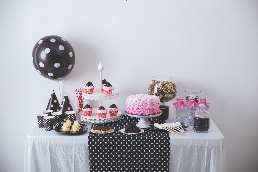 sur une table décorée d'une nappe blanche et de dessus de table noir, reposent de jolies décorations noires et roses.