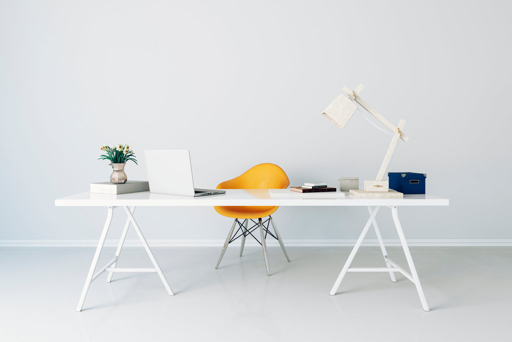 on y voit un bureau blanc laqué très design devant un mur blanc. la chaise de bureau jaune ressort dans un décor avec des éléments blancs sur le bureau.