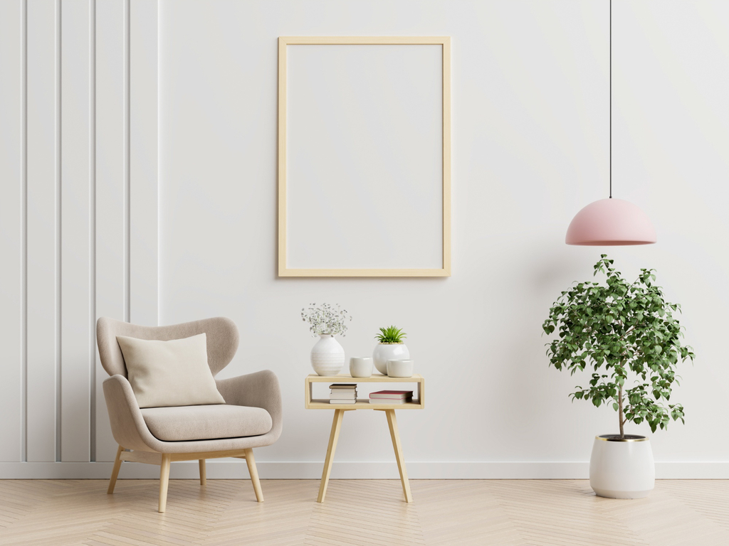 vue sur un salon design dont la couleur dominante est la couleur crème. on y voit un fauteuil, une console, un cadre en bois, une plante verte, un luminaire suspendu rose