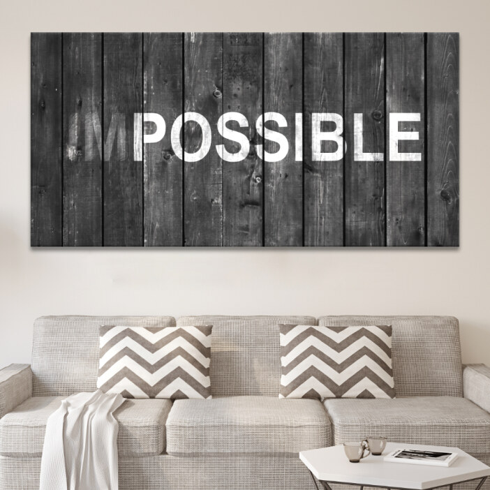 Tableau motivation impossible accroché au-dessus d'un canapé beige avec coussins à motifs