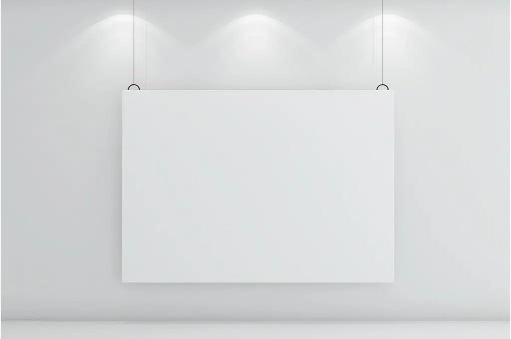 devant un mur blanc, une toile blanche est accrochée avec un kit cimaise qui consiste en 2 câbles suspendus qui retiennent le tableau.