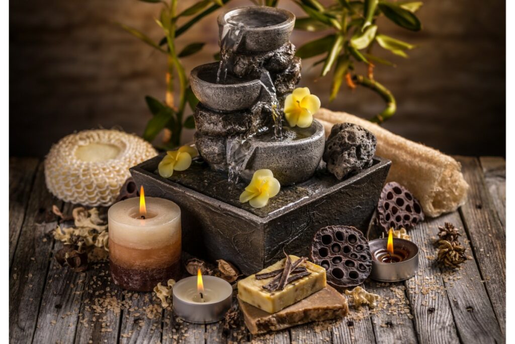 fontaine d'intérieur en pierre posée sur une table en bois. plusieurs bougies allumées sont disposées autour.