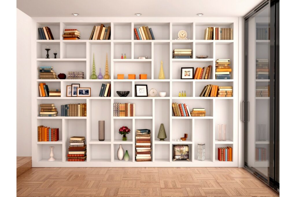 une grande bibliothèque blanche prend l'espace sur tout un grand pan de mur. divers objets y sont exposés dont majoritairement des livres, vases et cadres photo.