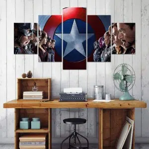 sur fond gris un tableau en 5 pièces qui représente les héros de marvel avengers qui sont alignés et se font face, devant lécusson de captain américa. En dessous du tableau un bureau en bois.