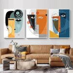 Tableau visage abstrait représentant trois visages abstraits sur chaque tableau accroché dans un salon au-dessus d'un grand canapé de cuir marron clair avec des coussins et un plaid et une table basse ronde