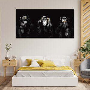 Tableau trois singes de la sagesse accroché au mur d'une chambre au-dessus d'un lit avec un couvre-lit et des coussins jaunes et entouré de tables de nuit en bois clair