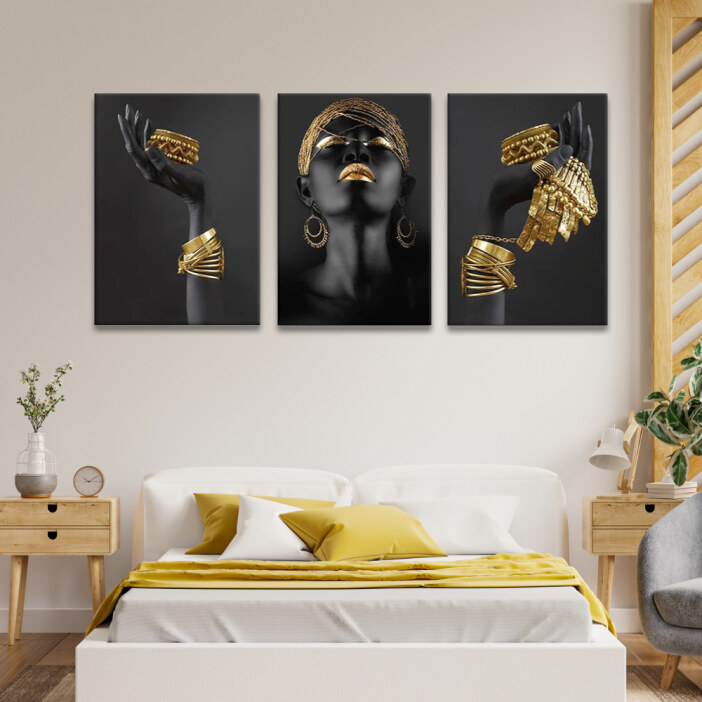 Tableau visage de femme africaine et bijoux dorés accroché au mur beige d'une chambre avec un lit aux couvertures jaunes et des touches boisées