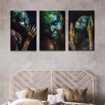 Tableau visage de femme noire au maquillage artistique accroché dans une chambre sur un mur beige au-dessus d'une tête de lit en bois façon rotin