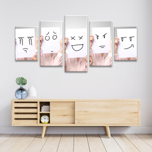 Tableau visage émotions dessinées façon émoticônes accroché au-dessus d'un meuble bas en bois clair avec portes coulissantes