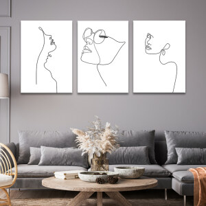 Tableau visage minimaliste sensuel affiché au mur gris d'un salon au-dessus d'un canapé gris foncé situé derrière une table basse en bois