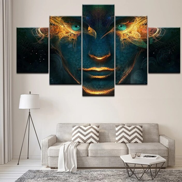 Tableau visage spirituel accroché au mur d'un salon aux couleurs claires au-dessus d'un canapé trois place gris avec coussins modernes et lampadaire à trois pieds avec table basse et tapis