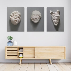 Les trois visages sculptés accroché au mur blanc d'un séjour au-dessus d'un meuble bas design en bois clair avec rangements