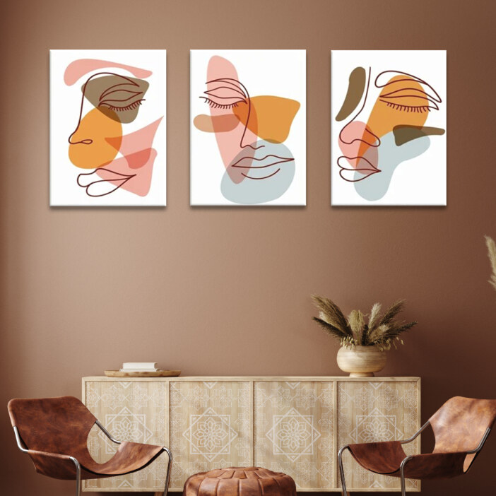 Tableau visage minimaliste aux yeux fermés affiché dans un séjour aux tons chauds avec mur taupe et meuble en bois clair ainsi que fauteuils en cuir marron