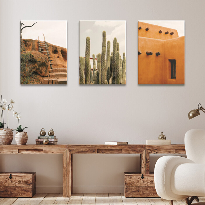 Tableau Mexique habitat traditionnel en milieu désertique Tableau Mexique habitat traditionnel en milieu désertique accroché dans un séjour au-dessus d'un meuble en bois foncé ouvert et d'un fauteuil blanc avec une lampe