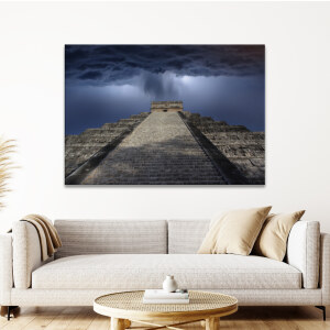 Tableau Mexique Chichén Itzá sous la pluie accroché au mur d'un salon au-dessus d'un canapé beige avec quelques coussins et une petite table basse ronde.