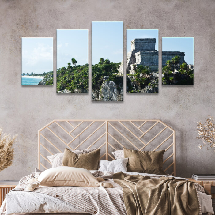 Tableau Mexique ruines de Tulum face à la mer des Caraïbes accroché dans une chambre au-dessus d'un lit aux draps beiges avec une tête de lit en rotin moderne.