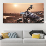 Un tableau d'une moto Harley Davidson au coucher du soleil accroché au-dessus d'un canapé de salon.