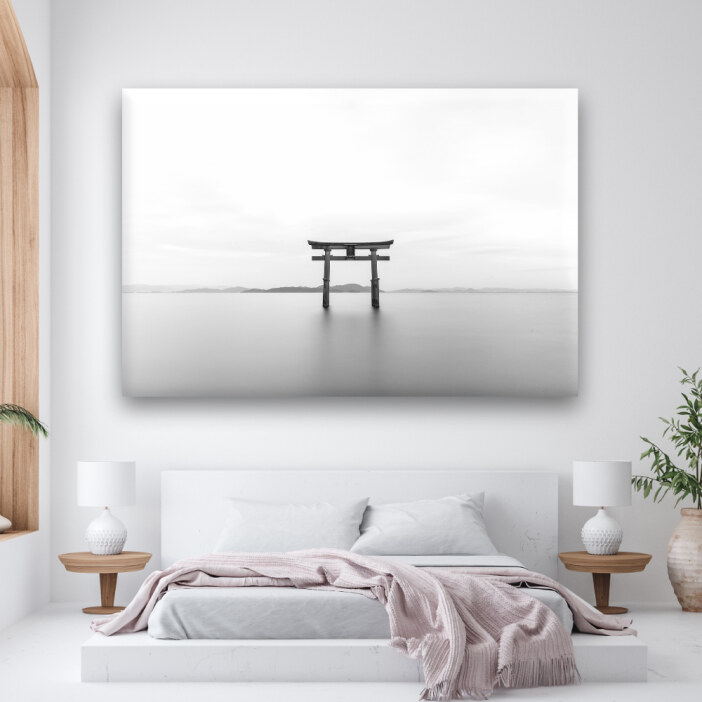 Un tableau en noir et blanc d'un torii japonais au-dessus d'un lit.